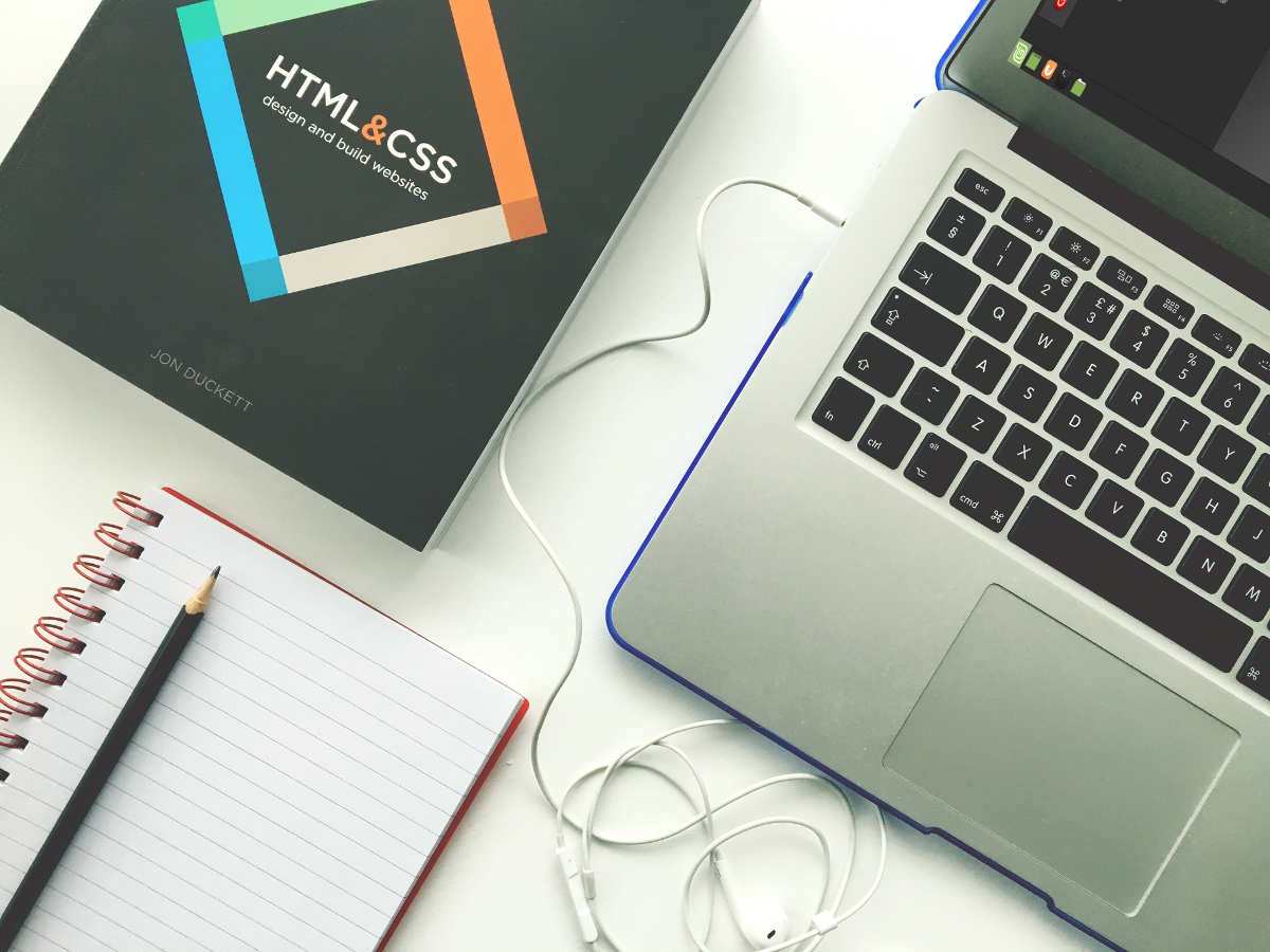 HTML and CSS book and the Orange Book with a notebook on a table